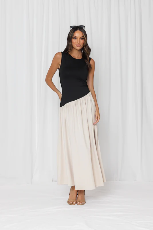 Woman wearing a black sleeveless top and cream skirt against a white background