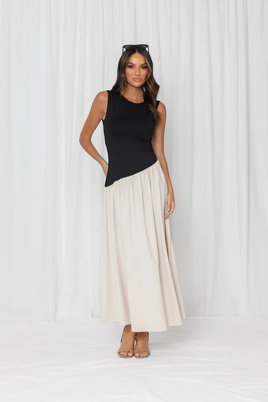 Woman wearing a black sleeveless top and cream skirt against a white background