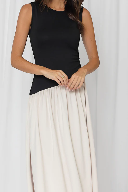 Person wearing a black sleeveless top and white skirt against a white background