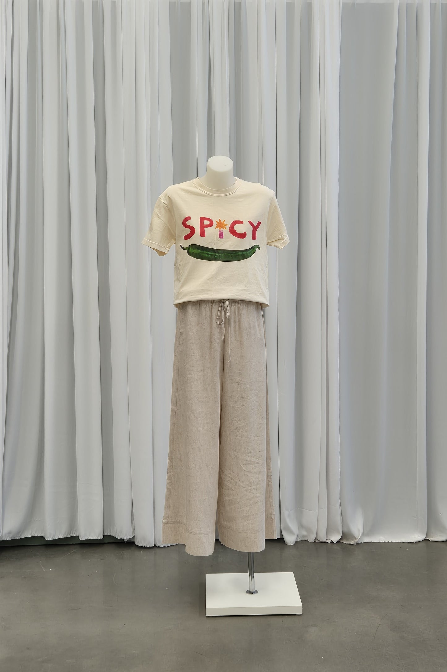 Front view of a soft cotton t-shirt in a light cream color, featuring a spicy  graphic design on the chest. The t-shirt has a crew neckline and short sleeves, perfect for casual wear or layering