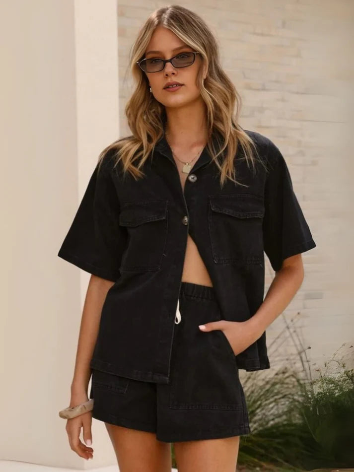 Woman wearing a black outfit with sunglasses against a neutral background